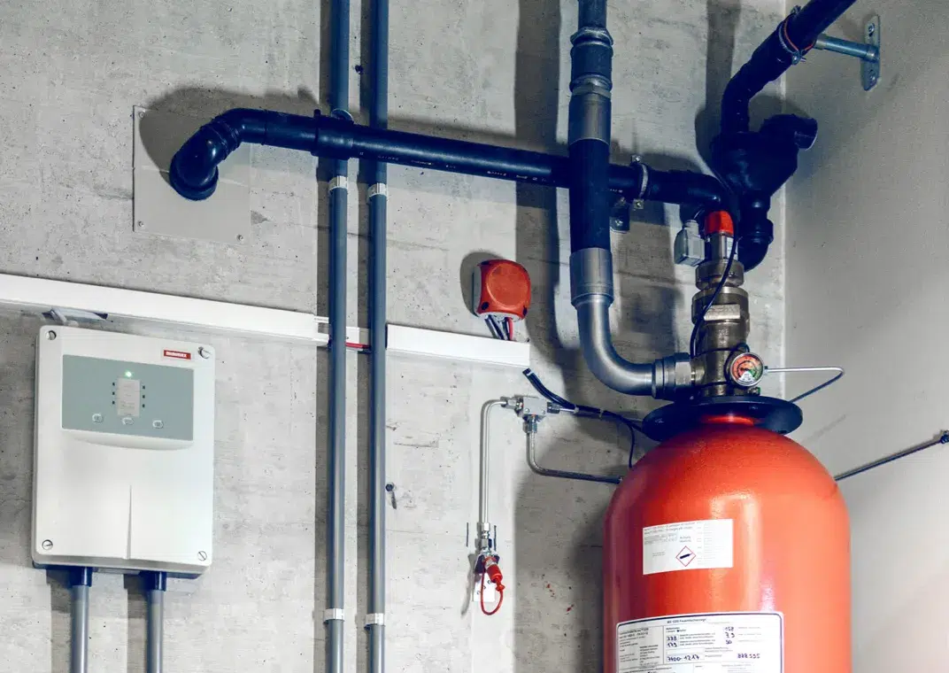 Aufnahme der automatischen Gas-Löschanlage in einem Server-Raum im Datacenter DATAROCK von hosttech. Ein grosser Feuerlöscher, an welchem verschiedene Rohre angebracht sind.