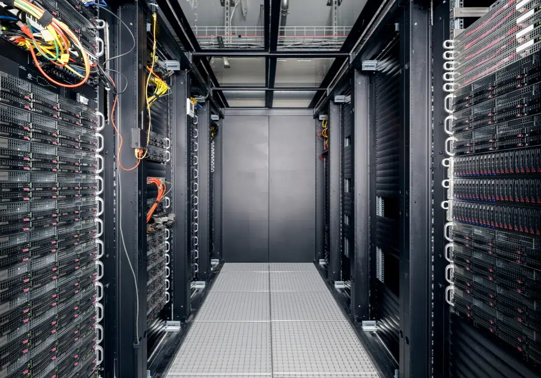 Innenansicht eines modernen Serverraums im Rechenzentrum – dicht bestückte Racks mit leistungsstarken Servern und strukturierter Verkabelung, Teil der hochverfügbaren IT-Infrastruktur von hosttech.
