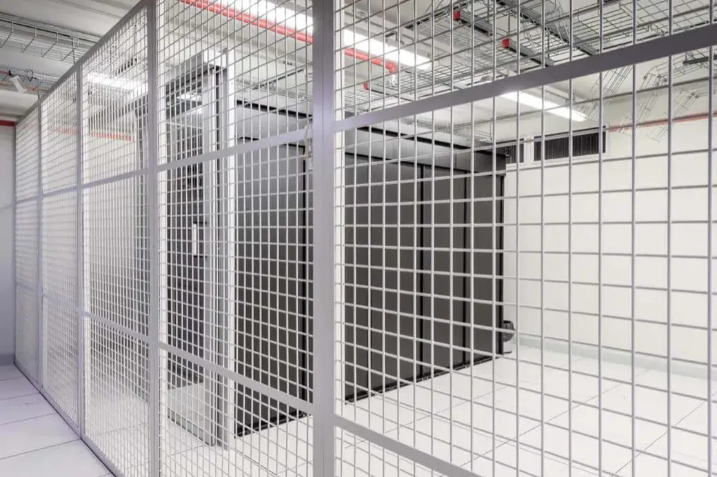 Visualisierung eines Private Cages im Colocation-Angebot von hosttech. Zu sehen sind Server-Racks, welche mit einem zusätzlichen Sicherheitsgitter vom restlichen Raum abgetrennt sind.